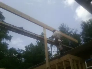 Carpenter setting a ridge beam over a new addition frame — Ice Dam Removal by Roofing Brothers in Kasson