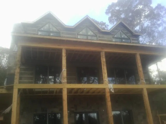 Dormers and porch framing on a large log home under construction — Roof Coating work by our crew in Kasson