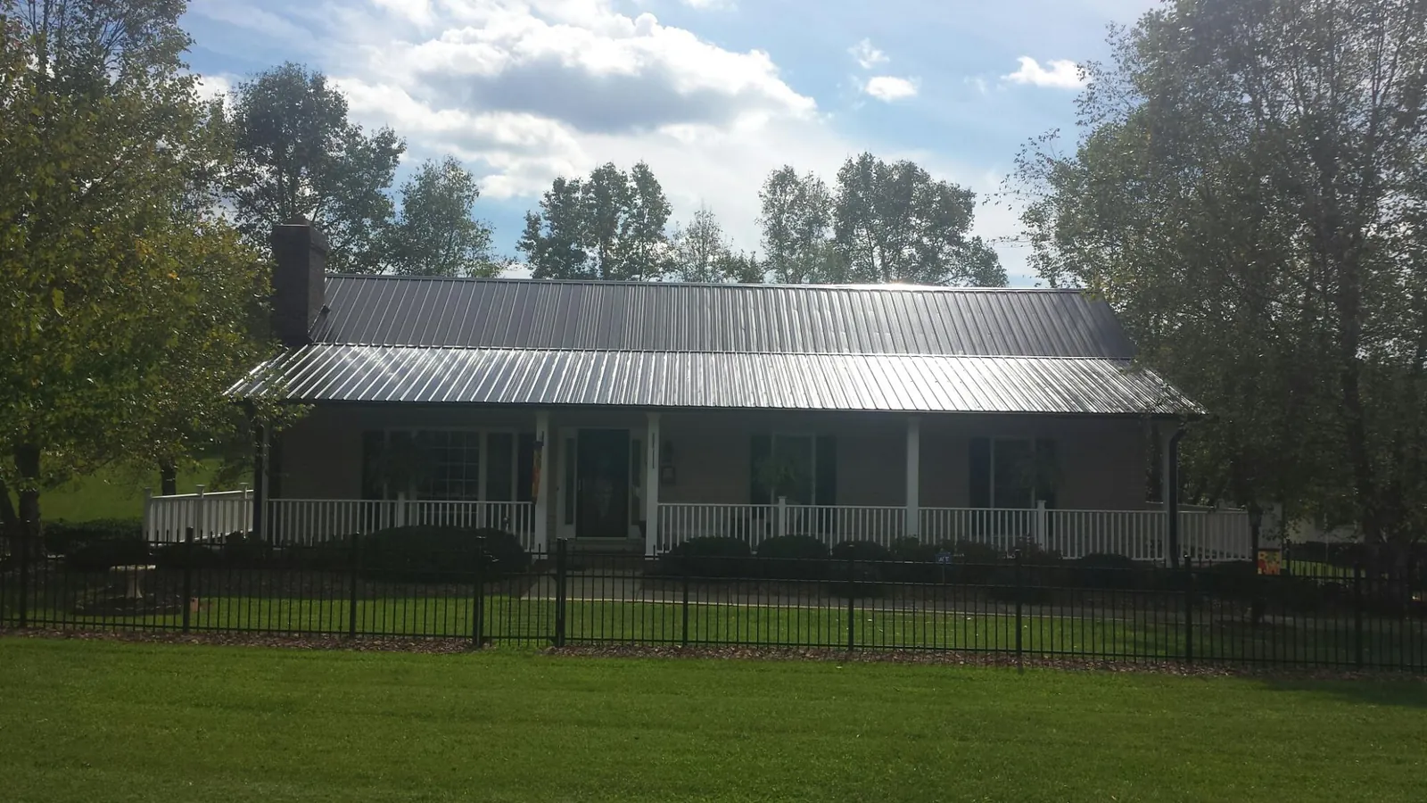 Gray metal roof on a brick ranch with a full width front porch — Gutter Guard Installation work by our crew in Kasson