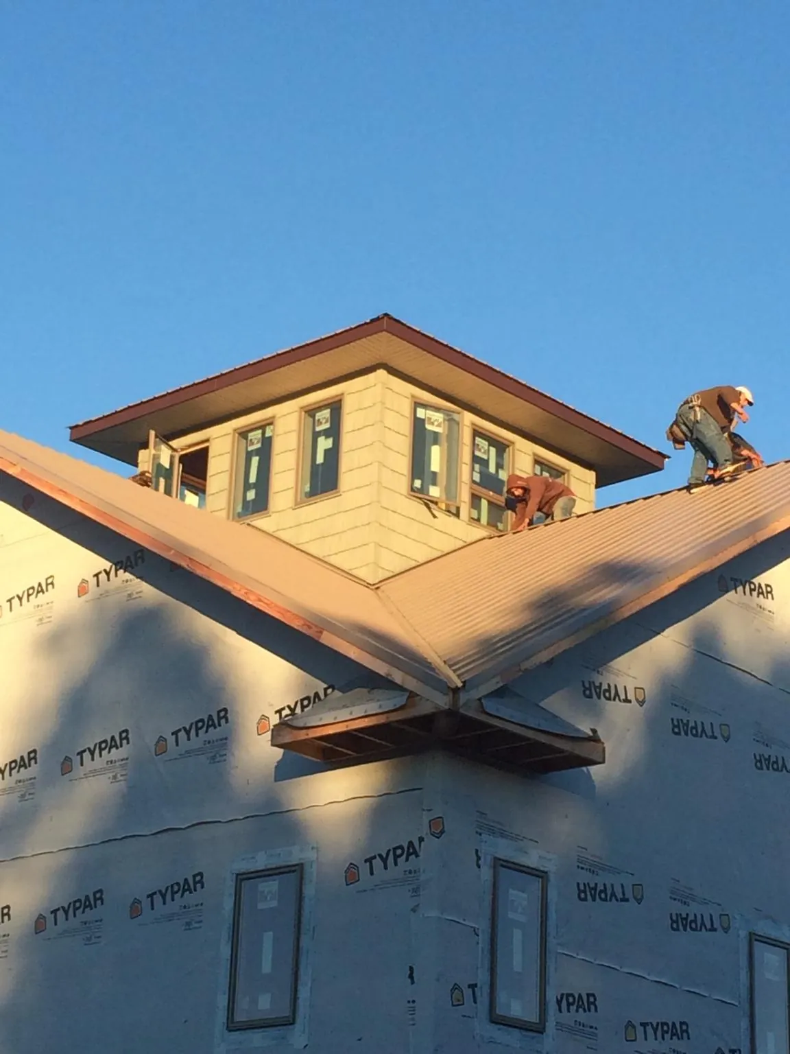 Roofers working around a rooftop cupola on a new metal roof at sunset — Roof Waterproofing in Kasson by Roofing Brothers